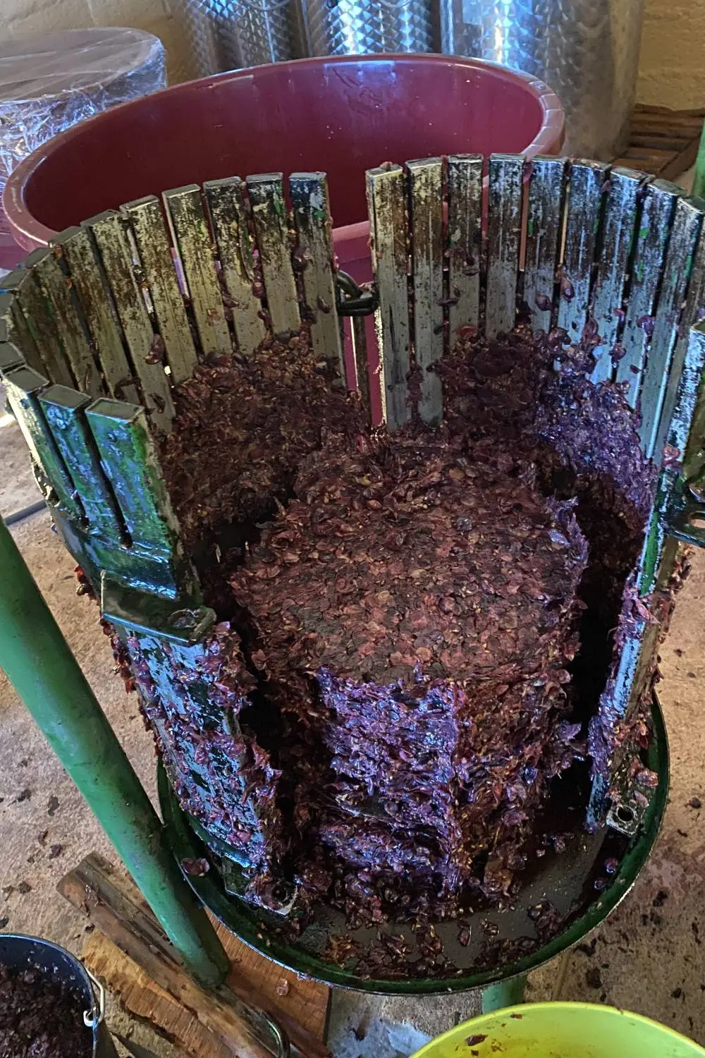 (EN) A small vertical press full of red grape skins.