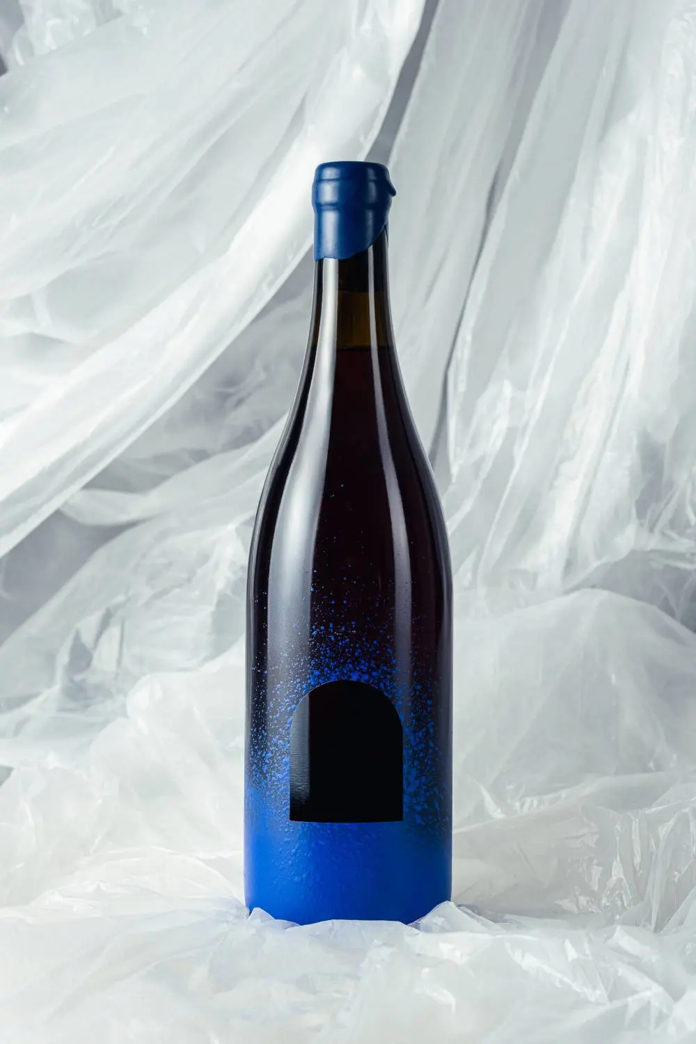 Photo of bottle of wine with blue spray paint and a window cutout.