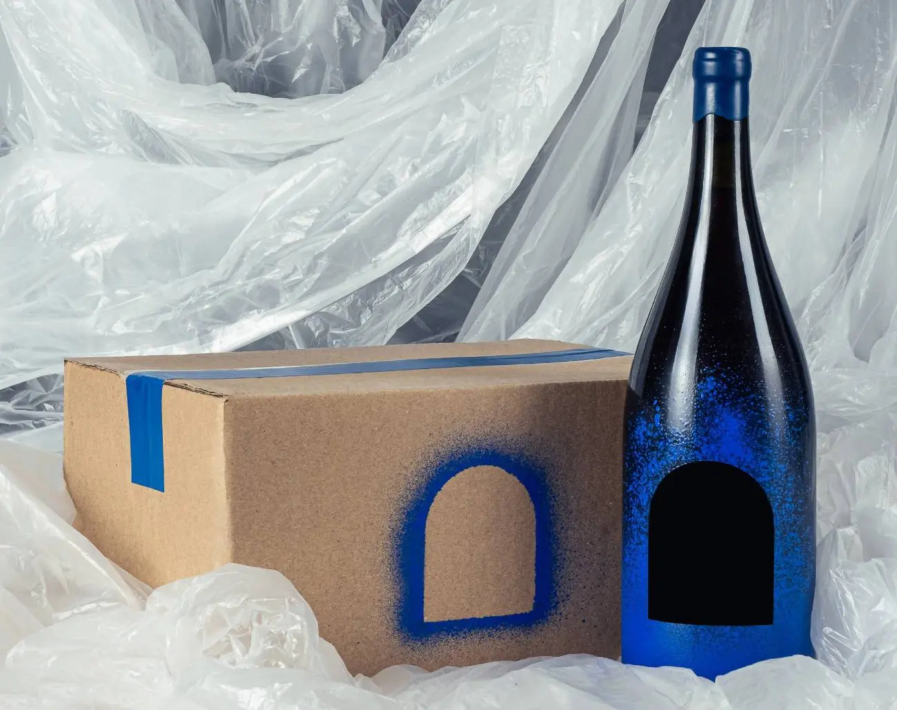 A large bottle with a blue cutout window next to a box.